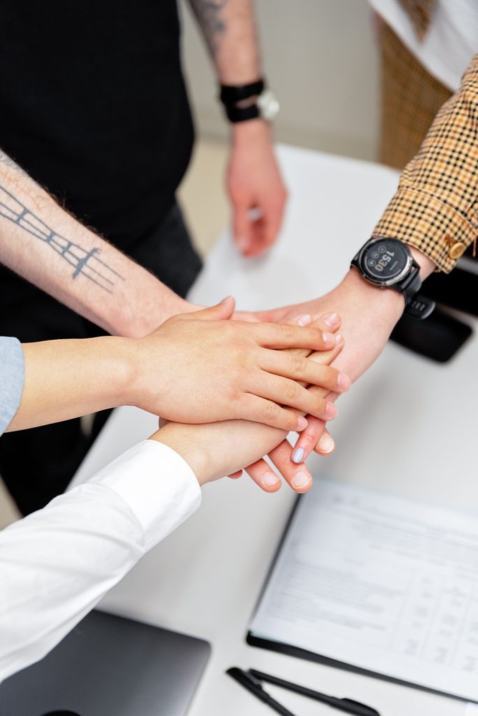 Close-up of a 'hands in' in a business environment, symbolising trust and partnership in Security Consultancy.